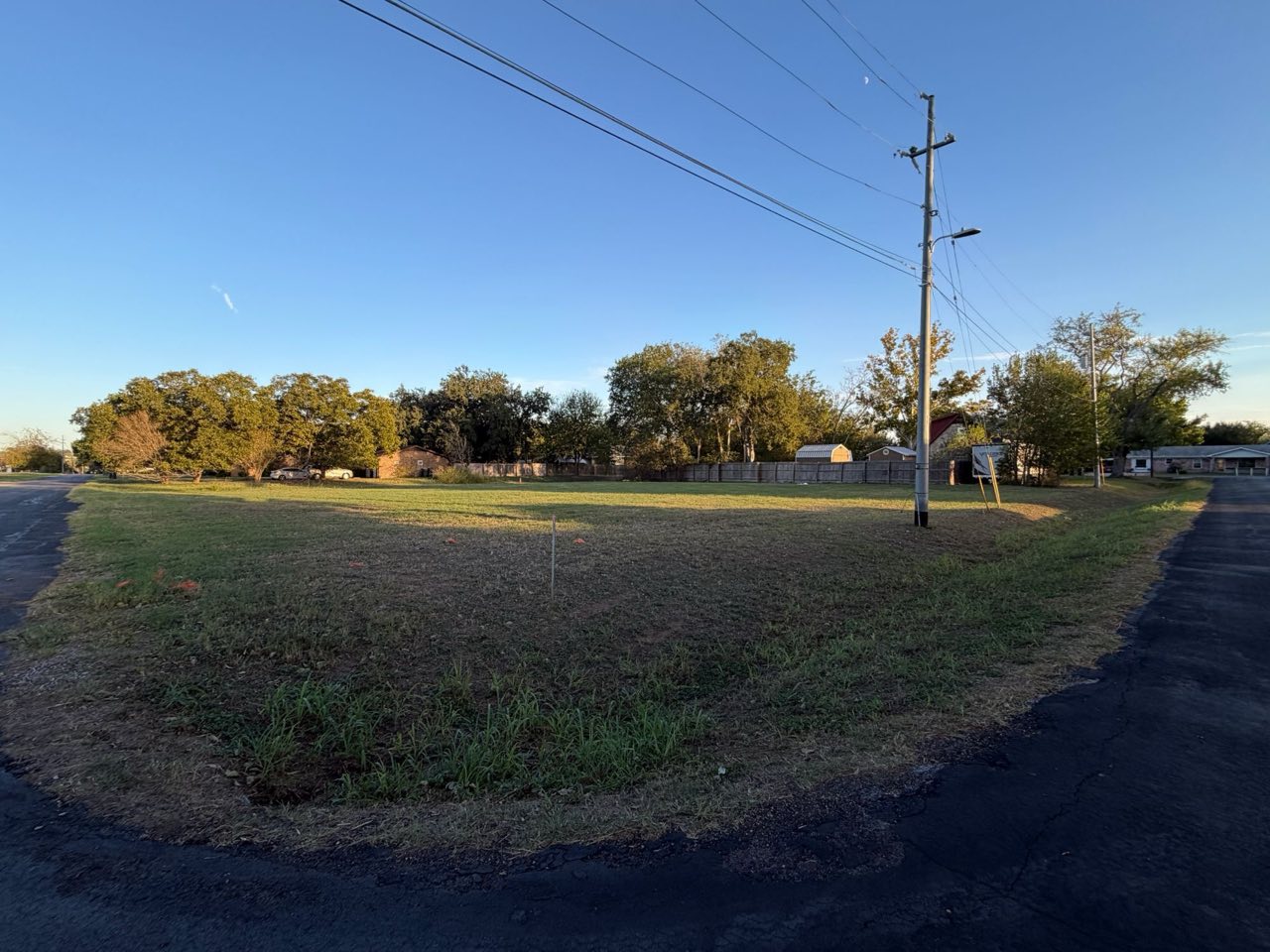 The curved corner of the lot with a utility pole and open grass