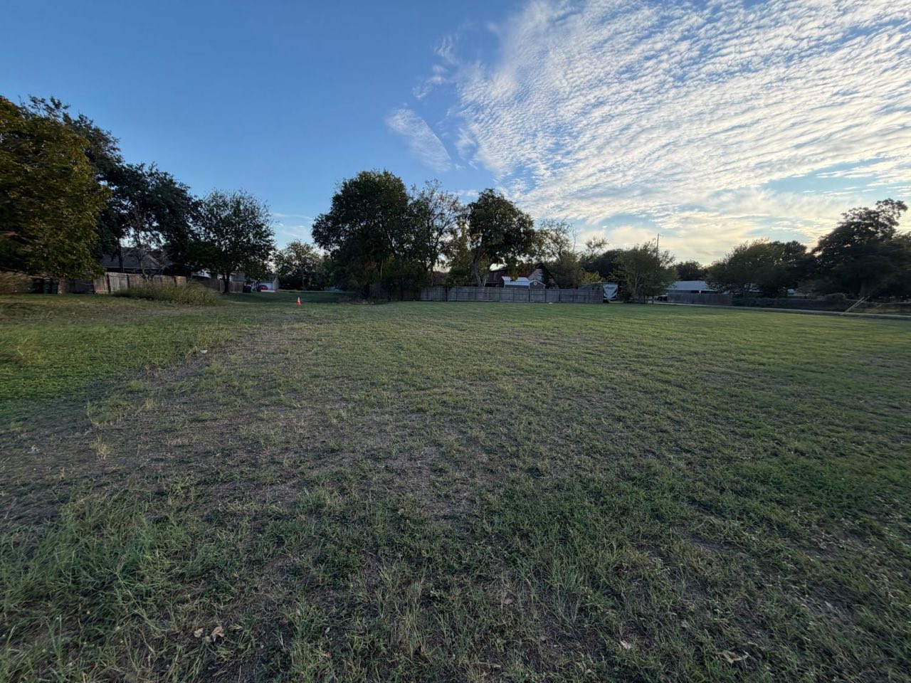 Wide view across the level, open grass lot under a blue sky