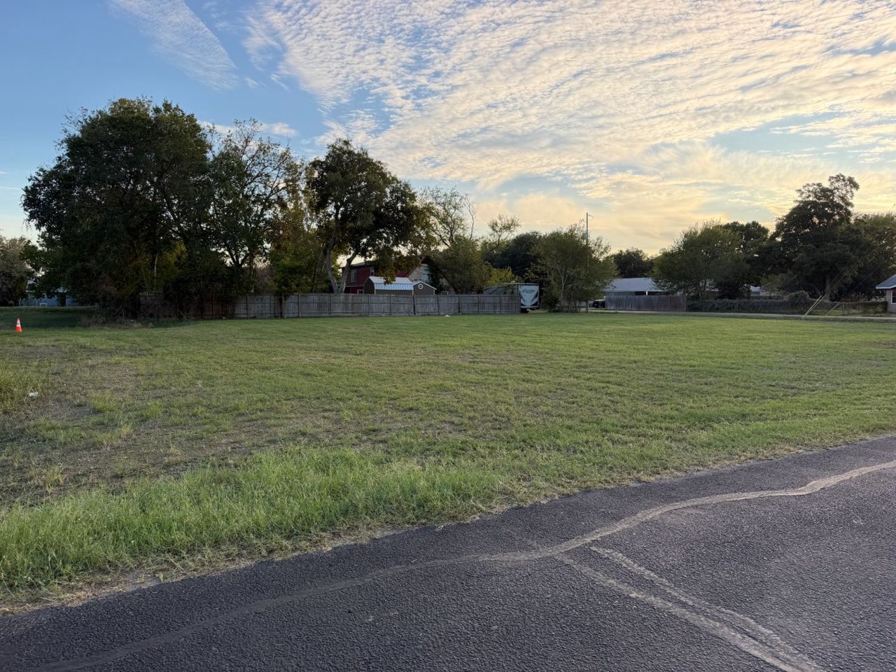 The lot from the street edge, with trees along the back