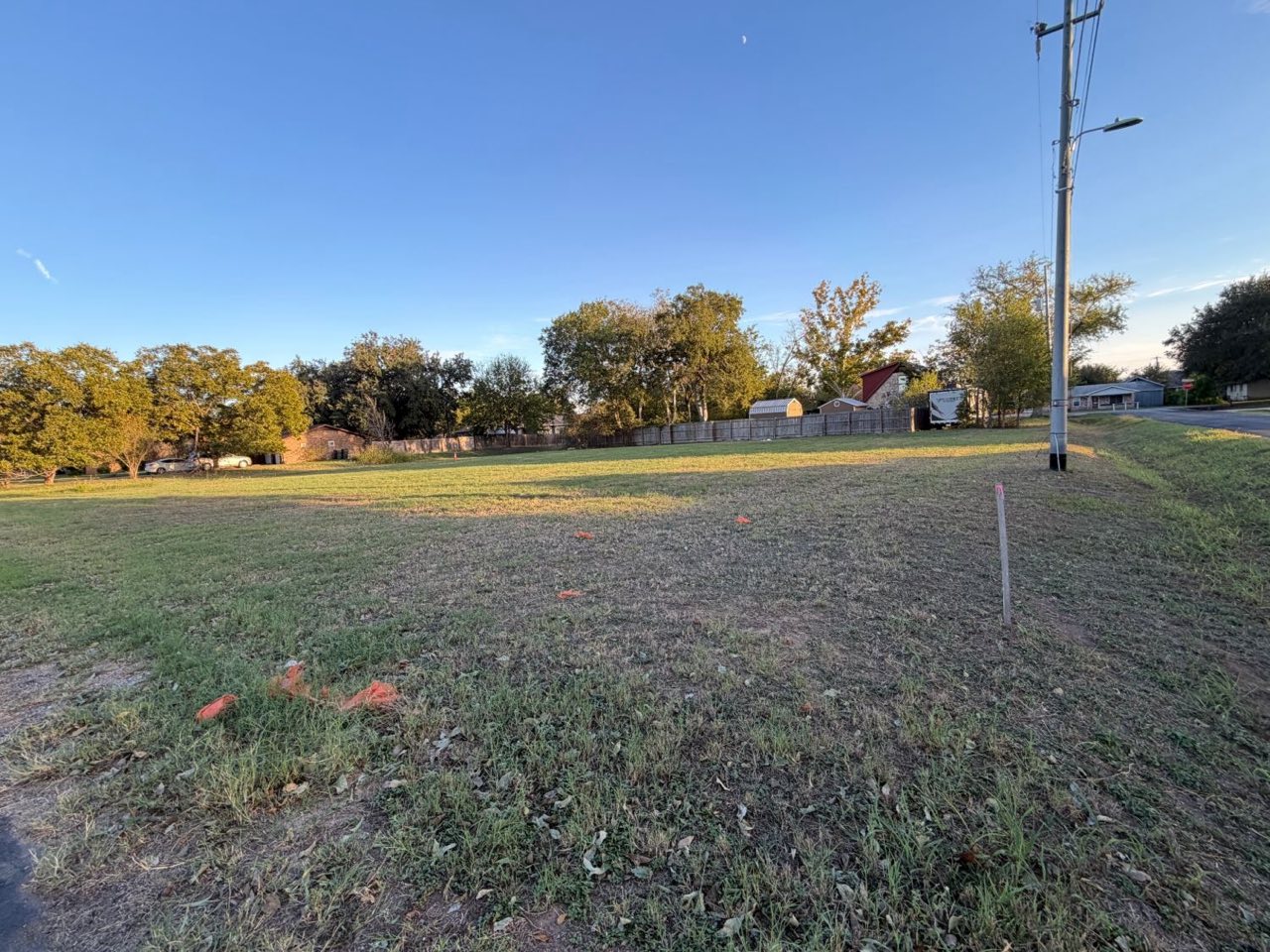 Open lot seen from the street side, with a utility pole at the right